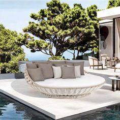 an outdoor living area with couches and tables next to the pool in front of it