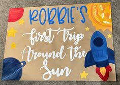 a cardboard sign with the words robbie's first trip around the sun on it