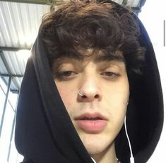 a young man with ear piercings wearing a hoodie