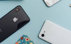 several different cell phones sitting on top of a blue table next to an apple phone