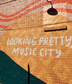 a brick wall painted with the words looking pretty music city on it's side