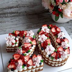 a number shaped cake sitting on top of a cutting board next to a vase with flowers