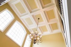 a chandelier hanging from the ceiling in a room with two windows above it