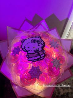 a hello kitty birthday cake with pink frosting and purple icing on top, surrounded by snowflakes