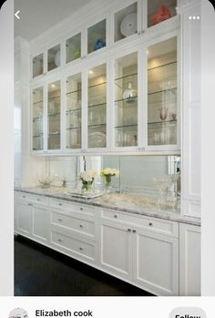 a kitchen with white cabinets and marble counter tops