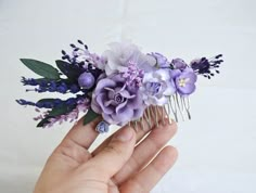 a hand holding a comb with purple flowers on it