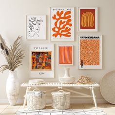 a white table topped with vases filled with flowers next to pictures on the wall