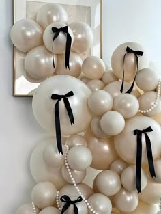 a bunch of balloons that are in the shape of a wreath with black ribbon and pearls