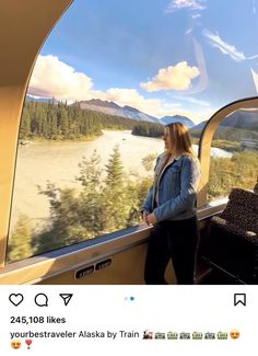 a woman standing in front of a window looking out at the mountains and lake below