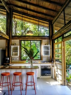 a kitchen with three stools in front of the counter and an open floor plan