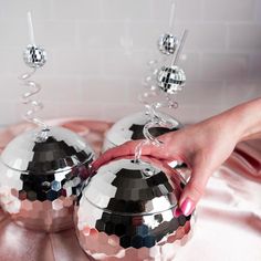 two shiny silver balls are being held by a woman's hand