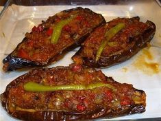 three stuffed peppers sitting on top of a white plate covered in sauce and seasoning