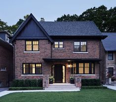 a large brick house with lots of windows and lights on the front door is lit up at night