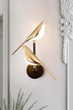 a wall mounted light with two birds on it