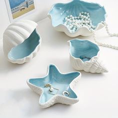 three starfish shaped dishes are sitting on a white table with beads and other items