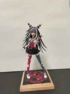 a figurine is standing on top of a wooden base with long black hair