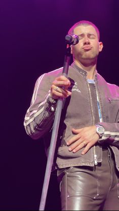 a man holding a microphone in his right hand and wearing leather pants on the other side