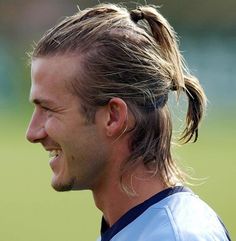 a man with long hair wearing a ponytail in a soccer uniform looking to his left