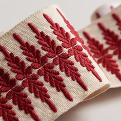 two red and white snowflakes are on the side of a piece of fabric