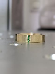 a close up of a gold ring with a green stone in the center on a table