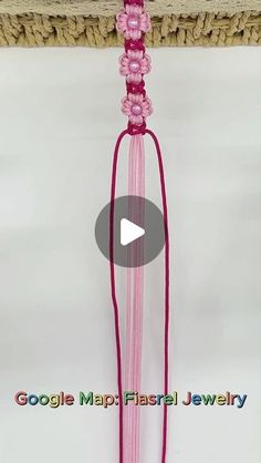 a pink tassel hanging from a rope on top of a white wall with the words google