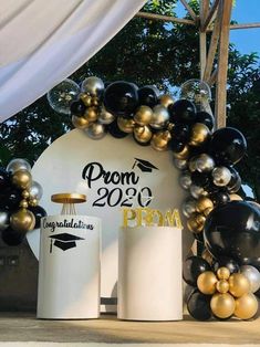 an arch decorated with balloons and black and gold confetti is the focal point for this graduation celebration