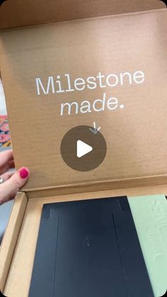 someone holding up a cardboard box that says, milestone made