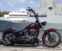 a red and black motorcycle parked in front of a large ship