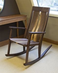 a wooden rocking chair sitting in front of a window