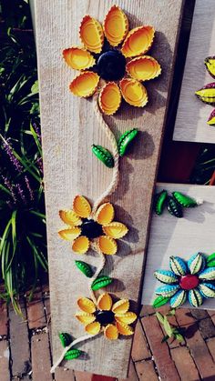 some yellow and green flowers are sitting on a wooden board next to other pieces of art