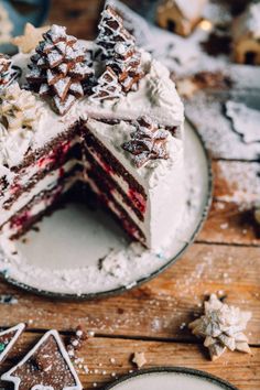 a slice of red velvet cake with white frosting on a plate next to cookies