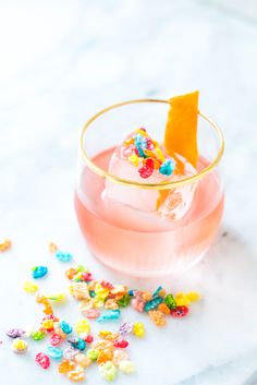 two glasses filled with candy sprinkles and one has an orange slice on top