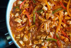 a pan filled with chicken and peppers on top of a stove next to an oven