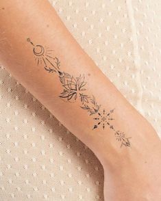 a woman's arm with a tattoo on it that has an arrow and flowers