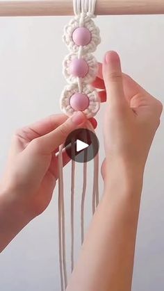 two hands are working on a crocheted beaded hair comb with pink beads