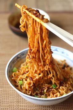 the noodles are being held up by chopsticks