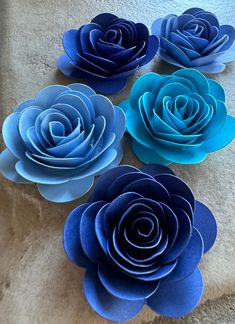 four blue paper flowers sitting on top of a white towel in the shape of roses