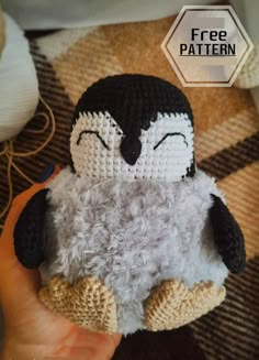 a hand holding a small crocheted penguin