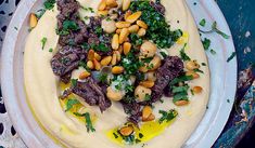 a white plate topped with meat, beans and parsley on top of a table