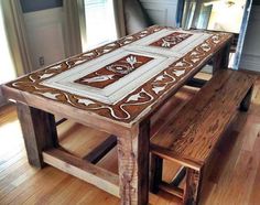 a wooden table sitting on top of a hard wood floor covered in white and brown tile