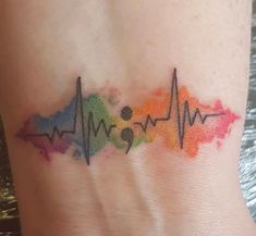 a watercolor heartbeat tattoo on the side of a woman's stomach, with colorful ink