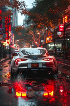 a white sports car driving down a rain soaked street in the city with red neon lights