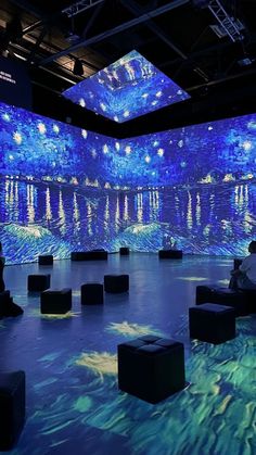 people are sitting on stools in front of a large screen with water and stars