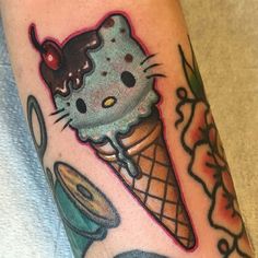 a hello kitty ice cream cone tattoo on the right arm and leg, with other items surrounding it