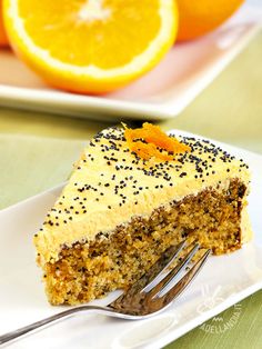 a slice of cake on a plate with a fork and oranges in the background