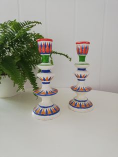 three colorful vases sitting on top of a table next to a potted plant