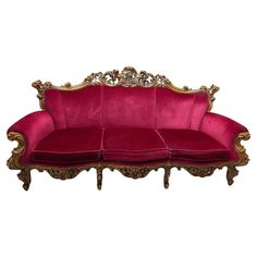 a red velvet couch with gold trimmings and ornate carvings on the armrests