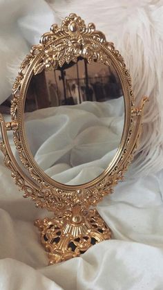 an ornate gold mirror sitting on top of a white blanket