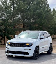 a white jeep is parked in front of some trees