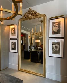 a large gold framed mirror sitting on top of a wall next to a chandelier